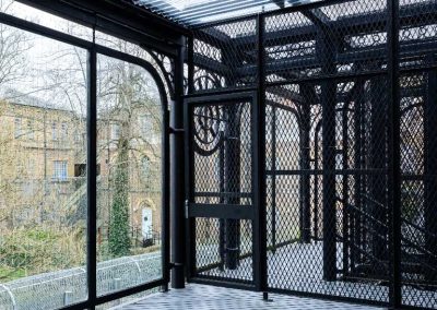 Enclosed walkway with black metal mesh.